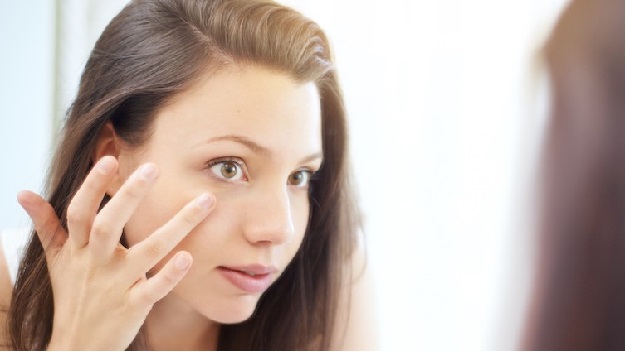 Over the shoulder shot of an attractive young woman looking at her reflection in a mirror
